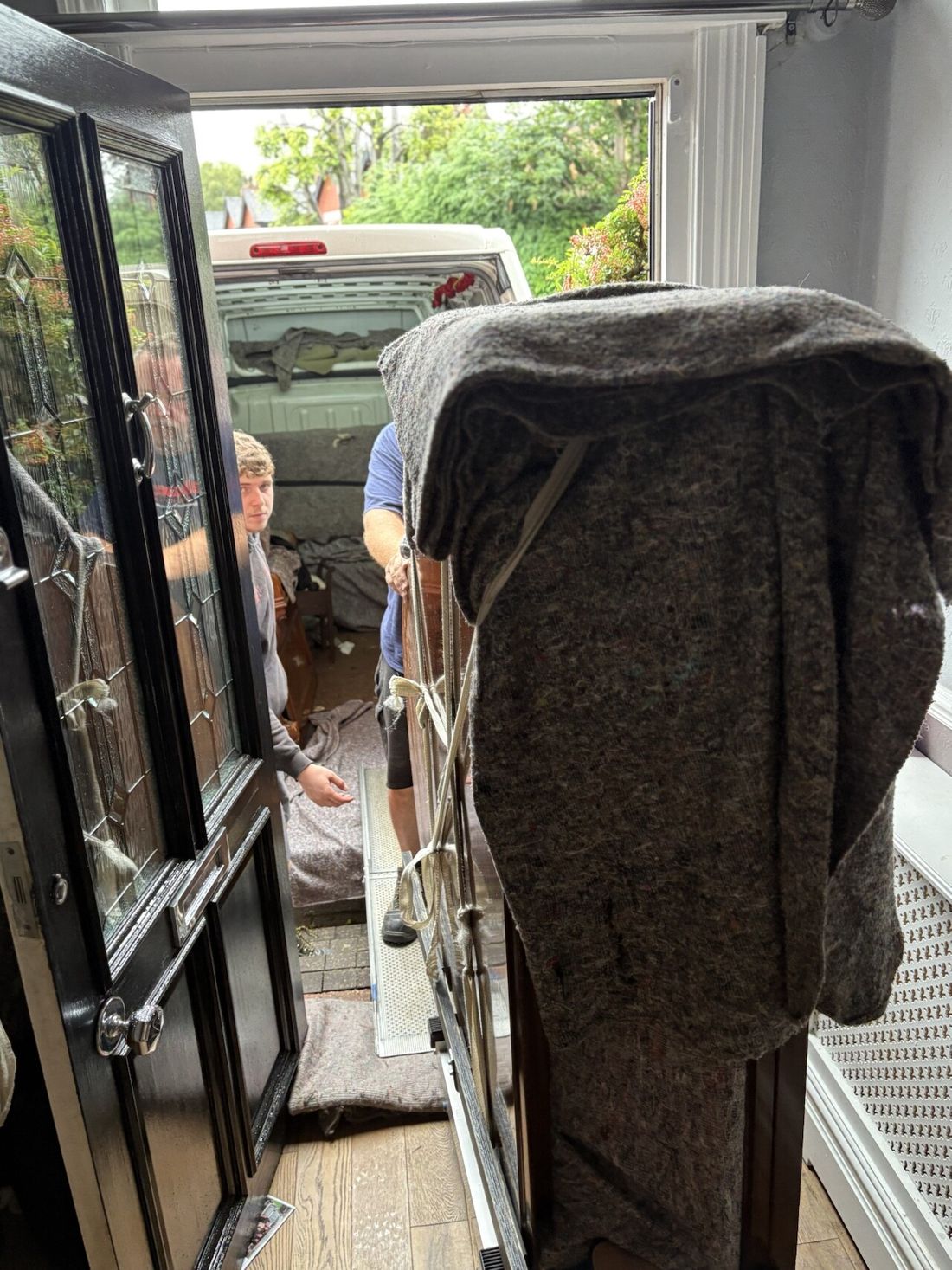 The team taking an upright piano down outside steps